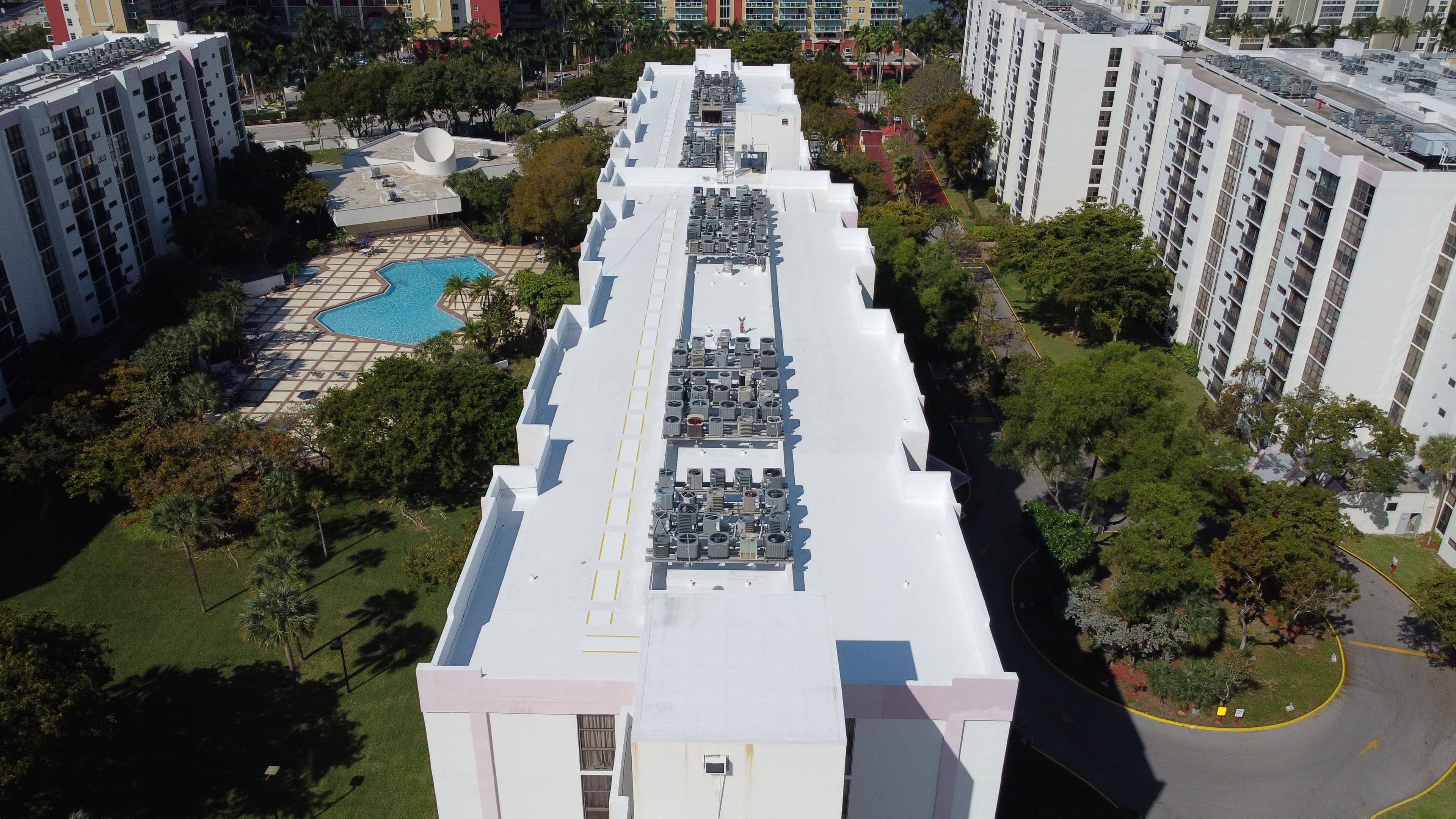 Aerial view of a rooftop with HVAC units, surrounded by landscaped grounds and a pool.