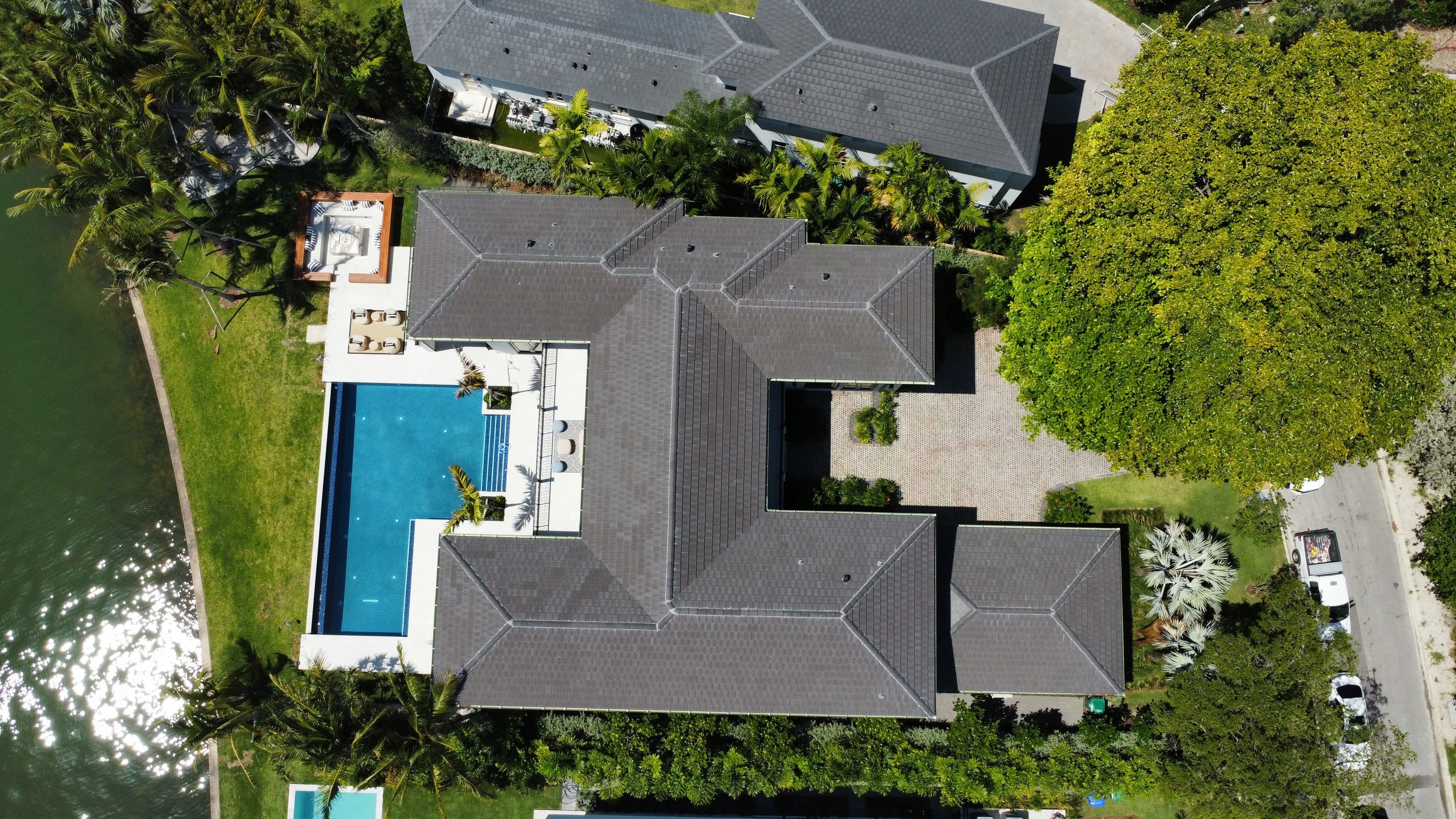 Aerial view of a large modern home with a pool surrounded by lush greenery.