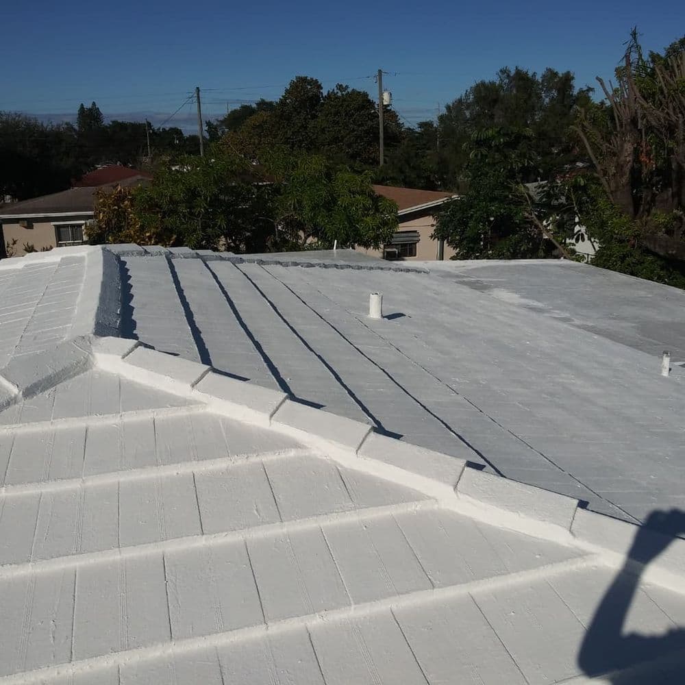 White roof with ridges under clear blue sky, showcasing residential roofing detail.