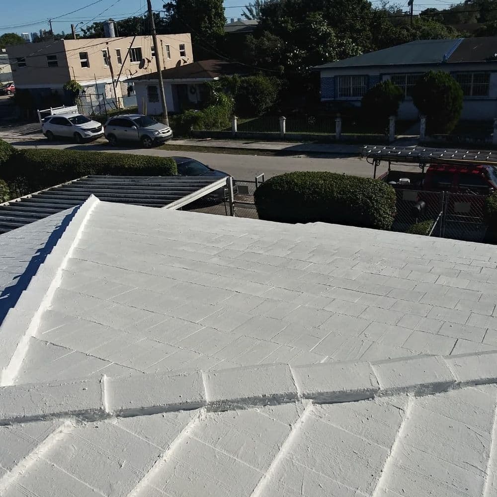 White flat roof with textured surface and residential neighborhood in the background.