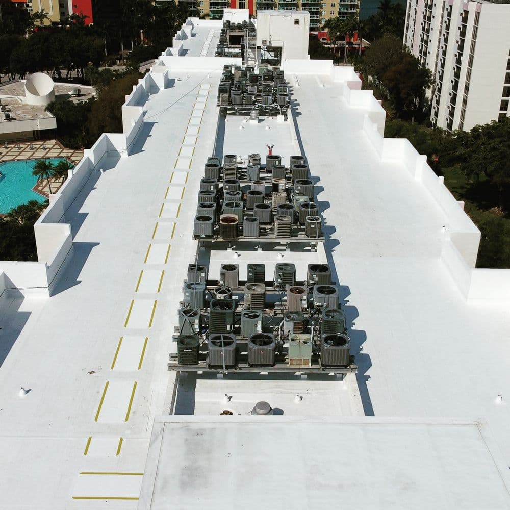 Roof view showcasing multiple HVAC units on a commercial building, with a pool in the background.