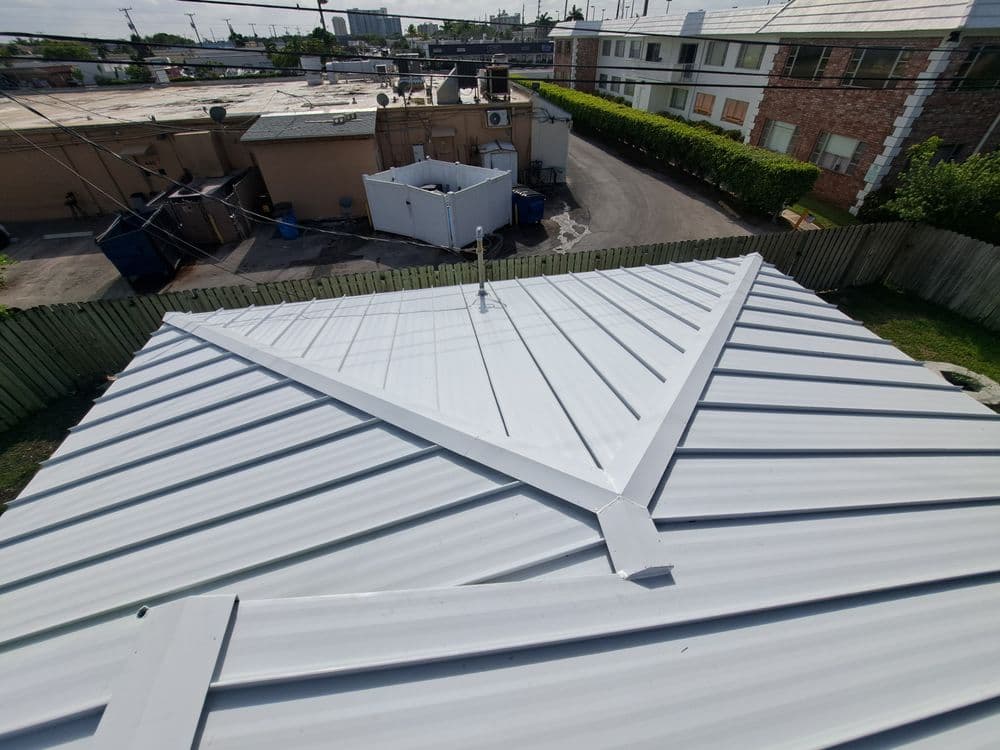 Metal roof installation with a view of rooftops and urban background. Bright daylight.