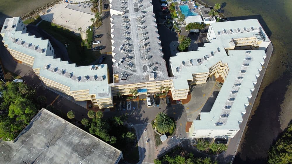 Aerial view of a spacious waterfront hotel with pool and landscaped grounds.