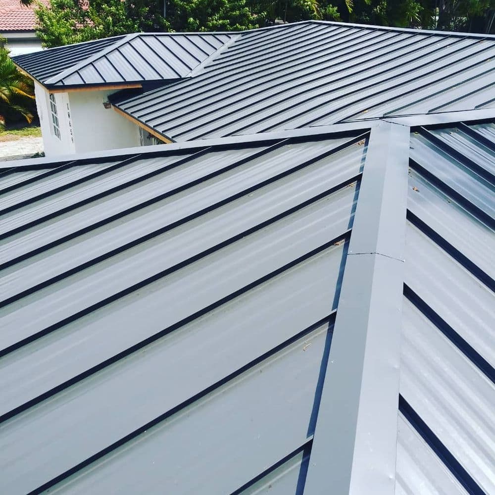 Modern metal roof installation with sleek, silver panels on a residential building.