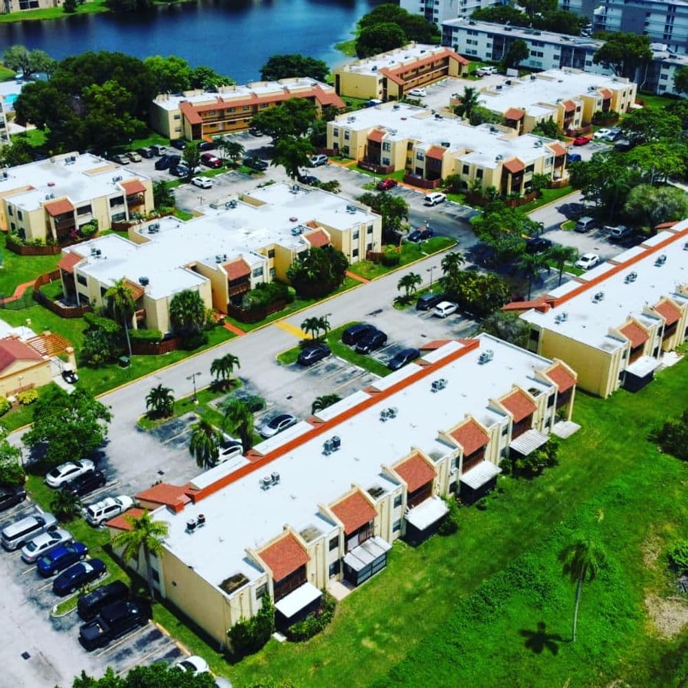 Aerial view of colorful residential apartments with parking near a lake.