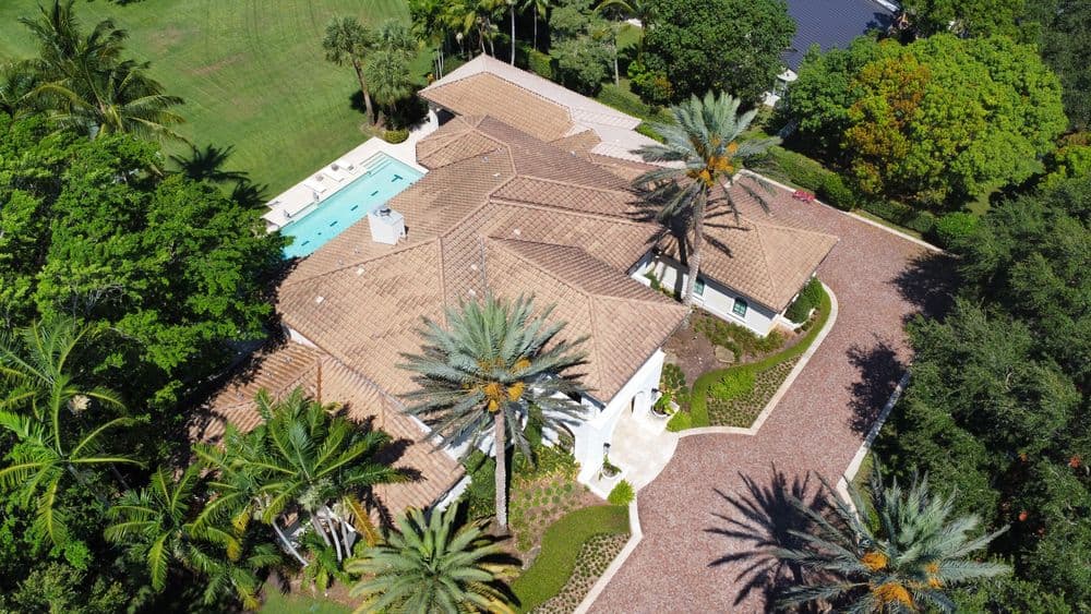 Aerial view of a luxury villa with a pool, palm trees, and landscaped grounds.