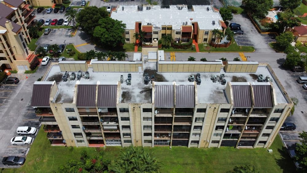 Aerial view of an apartment complex with multiple floors and rooftop AC units.
