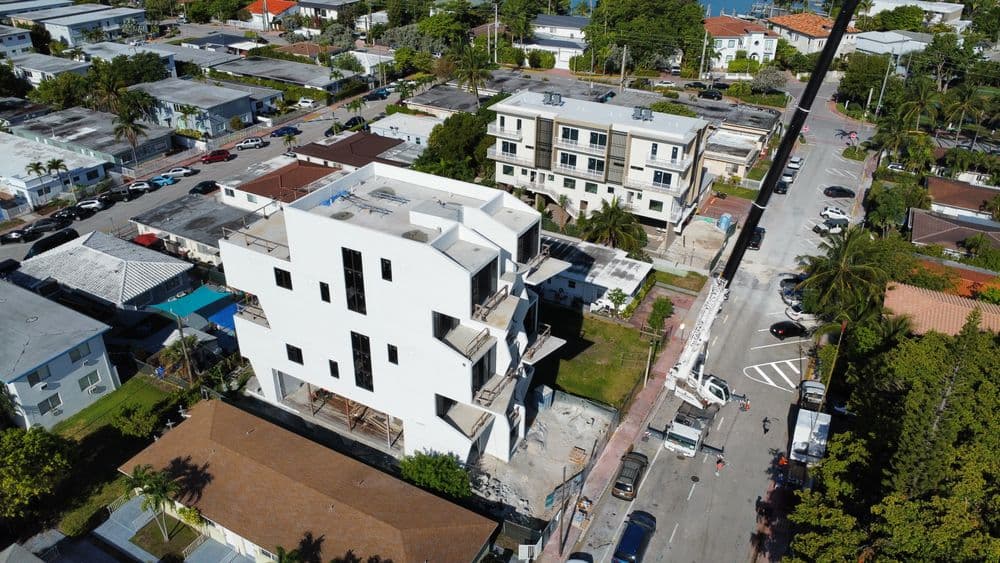 Aerial view of a modern, partially constructed building surrounded by residential homes and streets.