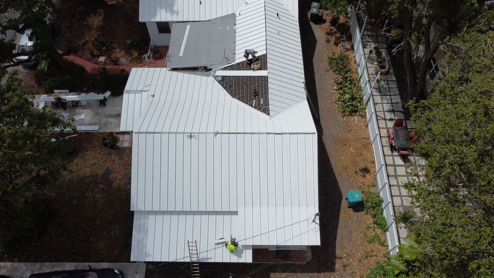 Aerial view of a roof installation with workers on a residential home.