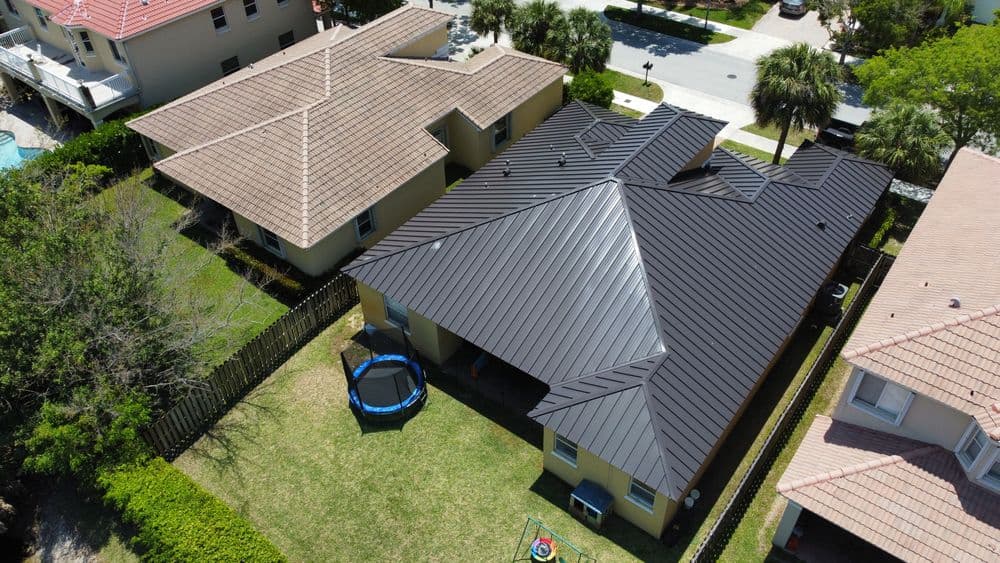 Aerial view of two homes with modern roofs, one featuring a trampoline in the yard.