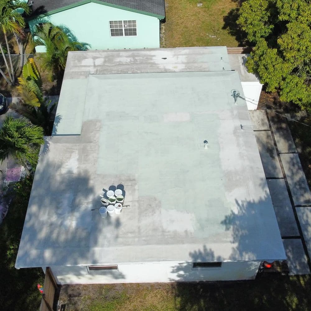 Aerial view of a flat roof with equipment and green landscaping nearby.