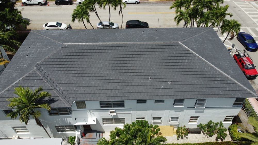 Aerial view of a modern flat roof with palm trees and parked cars in a residential area.