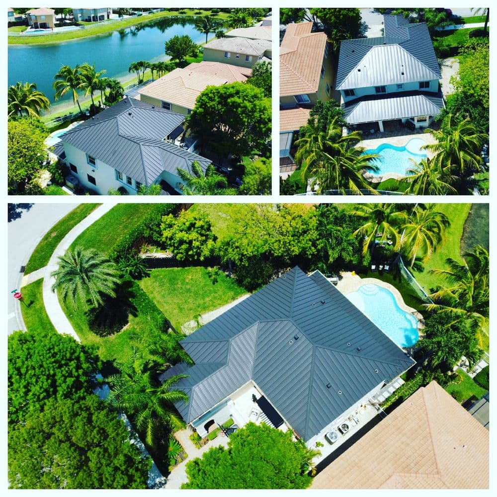 Aerial view of modern homes with black metal roofs and lush landscaping near a pool and lake.
