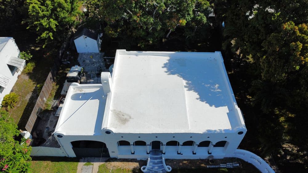 Aerial view of a white-roofed building surrounded by lush greenery.