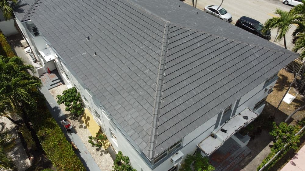 aerial view of a modern building with a gray tiled roof and surrounding palm trees